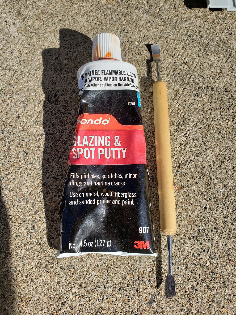 I am using Bondo spot putty as a light filler to fill in the deterioration  in the plastic around the window. This is the same material used to fill  pin